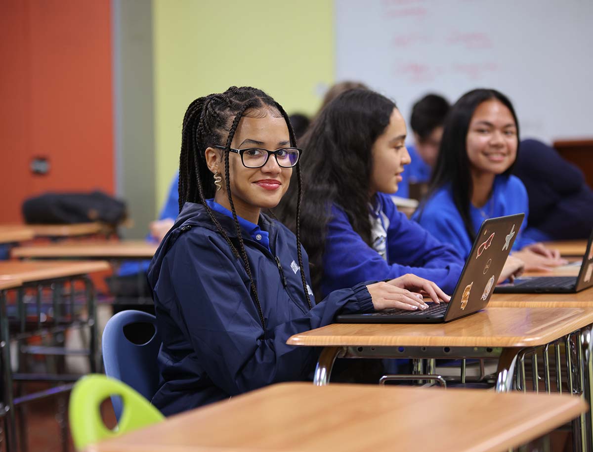 Elementary student smiling and posing together in a classroom.